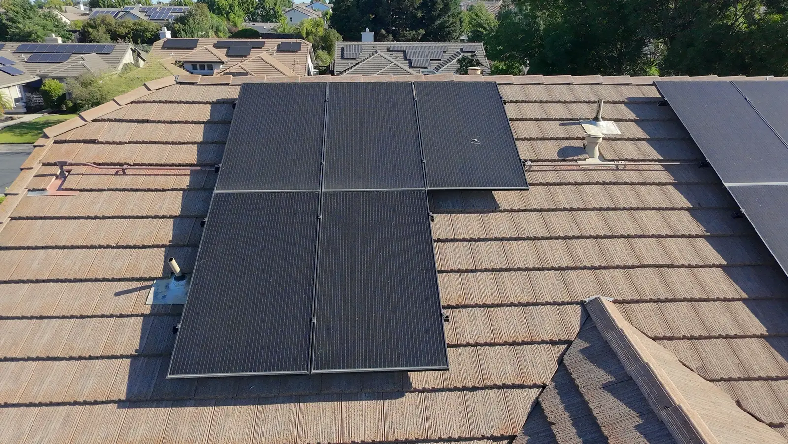 Rooftop solar panels coated in dust and pollen on a tile roof before professional solar panel cleaning