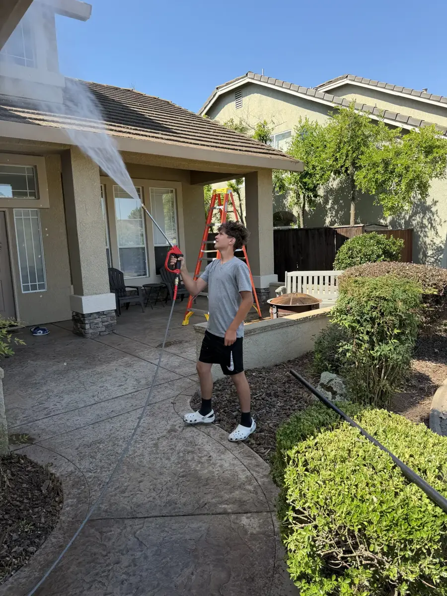 Cable Pressure Washing crew member rinsing gutter debris off a Placer County driveway after a gutter cleaning